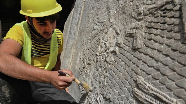 Рабочий занимается очисткой мраморных рисунков, возрастом около 2700 лет, найденных в Мосуле, Ирак - Sputnik Узбекистан