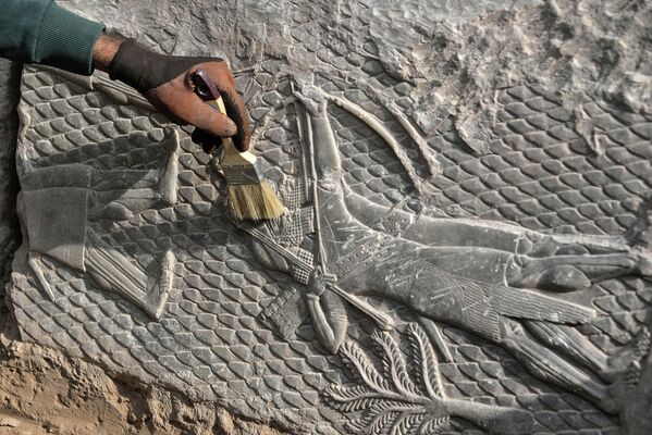 Рабочий очищает мраморную плиту с узором найденную в древнем ассирийском городе Ниневии. - Sputnik Узбекистан