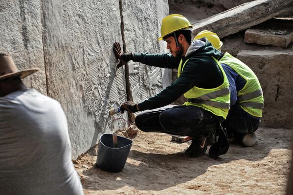 Рабочий очищает мраморную плиту с узором найденную в древнем ассирийском городе Ниневии. - Sputnik Узбекистан