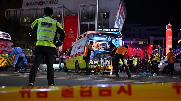 Сеульские спасатели помогают пострадавшим и вывозят погибших с улицы, где во время празднования Хэллоуина из-за давки остановилось сердце у десятков людей, Южная Корея - Sputnik Узбекистан