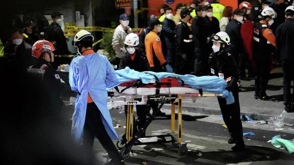 Спасатели несут пострадавшего на улице рядом с местом происшествия в Сеуле, где произошла давка
 - Sputnik Ўзбекистон