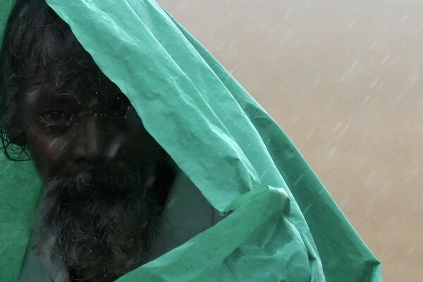 Мужчина под полиэтиленовой пленкой во время сильного муссонного дождя в Индии. - Sputnik Узбекистан