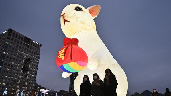 Люди проходят мимо освещенного фонаря в честь наступающего Года Кролика во время Сеульского фестиваля фонарей на площади Кванхвамун в Сеуле - Sputnik Узбекистан