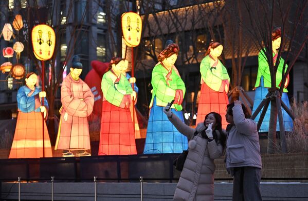 Молодая пара фотографируется во время фестиваля на фоне фонарей, выполненных в форме традиционных корейских нарядов &quot;хангбоков&quot;. - Sputnik Узбекистан