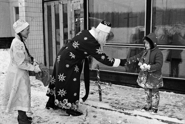 Дед Мороз и Снегурочка поздравляют девочку с Новым годом на улице города, 1985 год - Sputnik Узбекистан