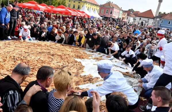 Боснийские повара и их ученики разрезают самый большой в мире пирог с мясным фаршем, известный как &quot;борек&quot;, на центральной площади острова Тузла. Он весил 650 кг и имел диаметр 6,5 м. Для его изготовления потребовалось 1,5 км вручную раскатанного теста. - Sputnik Узбекистан