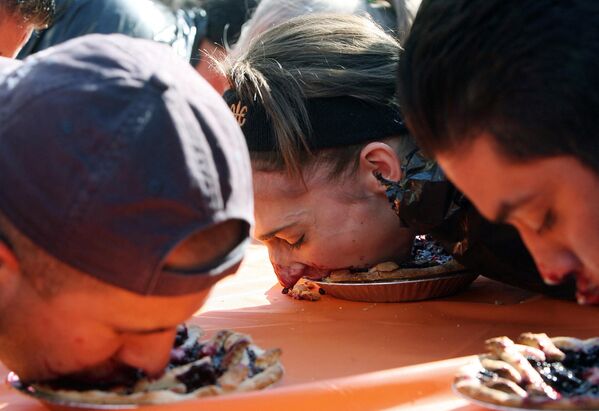 Люди участвуют в конкурсе по поеданию пирогов в Лос-Анджелесе. Победитель должен первым съесть пирог без помощи рук. - Sputnik Узбекистан