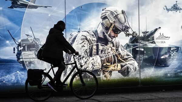 Мужчина на велосипеде проезжает мимо рекламного баннера возле штаб-квартиры крупнейшего немецкого производителя оружия Rheinmetall AG в Дюссельдорфе, Германия. Архивное фото - Sputnik Узбекистан