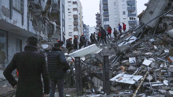 Люди и спасательные команды пытаются добраться до жителей, оказавшихся в ловушке внутри рухнувших зданий в Адане, Турция, понедельник, 6 февраля 2023 года. - Sputnik Узбекистан