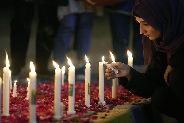 Женщина зажигает свечи во время всенощного бдения в память о жертвах землетрясения в Сирии и Турции, в Исламабаде, Пакистан, понедельник, 6 февраля 2023 года. - Sputnik Узбекистан