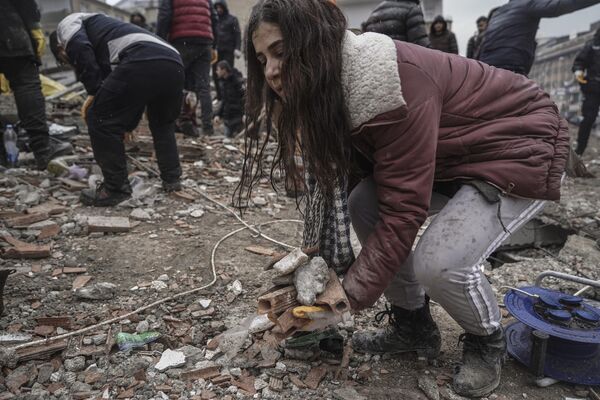 Молодая женщина убирает мусор из разрушенного здания в Газиантепе, Турция, понедельник, 6  февраля 2023 года. - Sputnik Узбекистан