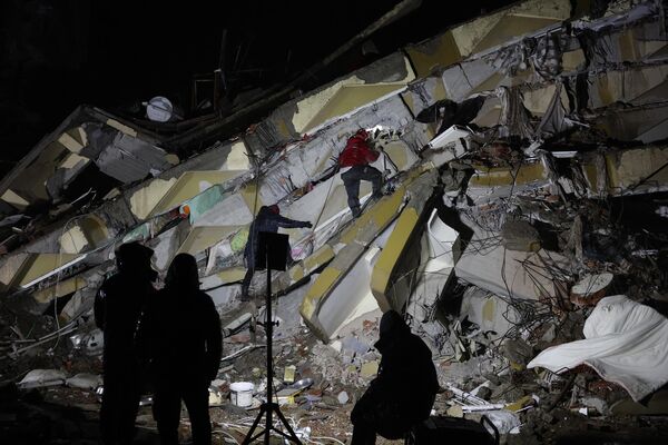 Спасатели ищут выживших среди обломков рухнувших зданий в  Кахраманмарасе, Турция, после землетрясения магнитудой 7,8 баллов, 7 февраля 2023 года. - Sputnik Узбекистан