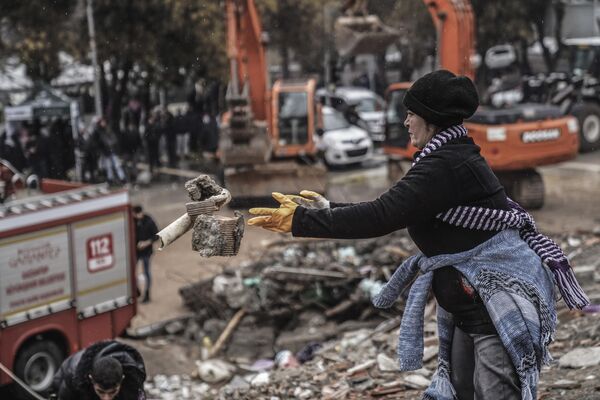 Женщина разбирает обломки разрушенного здания в Газиантепе, Турция, понедельник, 6 февраля  2023 года. - Sputnik Узбекистан