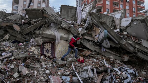 Мужчина в поисках людей в разрушенном здании в Адане, Турция, понедельник, 6 февраля 2023 года.  - Sputnik Узбекистан