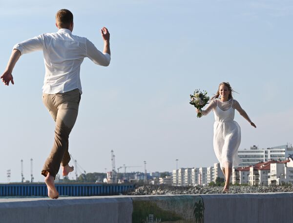 Новобрачные бегут друг к другу на набережной в Нижнеимеретинской бухте города Сочи. - Sputnik Узбекистан