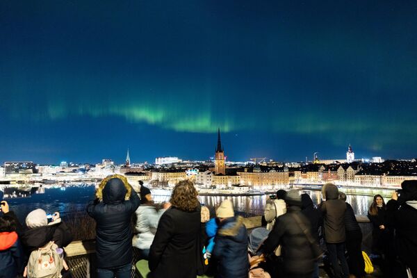 Люди наблюдают за северным сиянием в центре Стокгольма.  - Sputnik Узбекистан