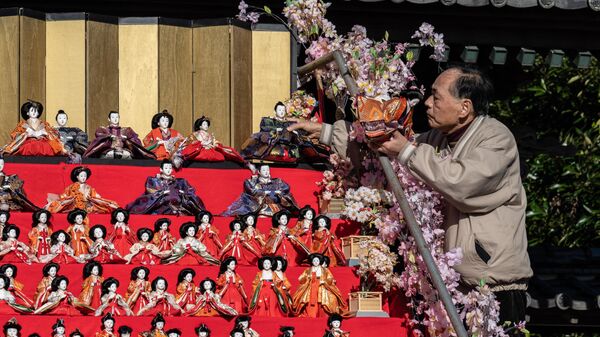Мужчина готовит японских декоративных кукол хина в храме Какуодзи во время фестиваля в городе Кацуура, префектура Тиба - Sputnik Узбекистан