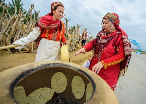 Женщины пекут в тандыре хлеб на праздновании Новруза в Ашхабаде.  - Sputnik Узбекистан