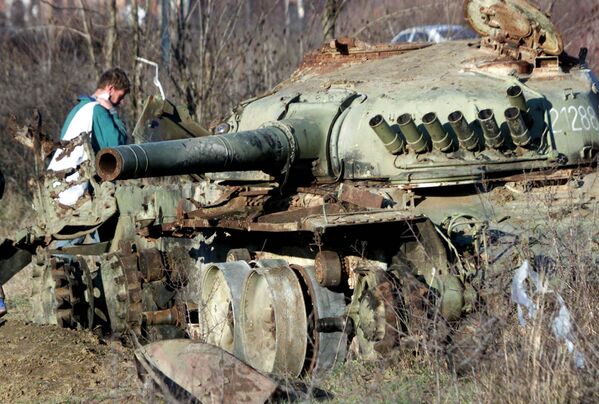 Албанец проходит мимо танка югославской армии, уничтоженного во время бомбардировок НАТО в городе Клина на западе Косово. - Sputnik Узбекистан