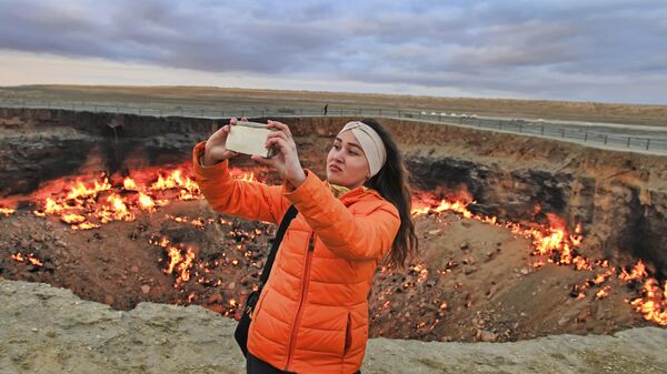 Девушка делает селфи на фоне горящего кратера Врата ада, пустыня Каракумы, Туркменистан - Sputnik Узбекистан