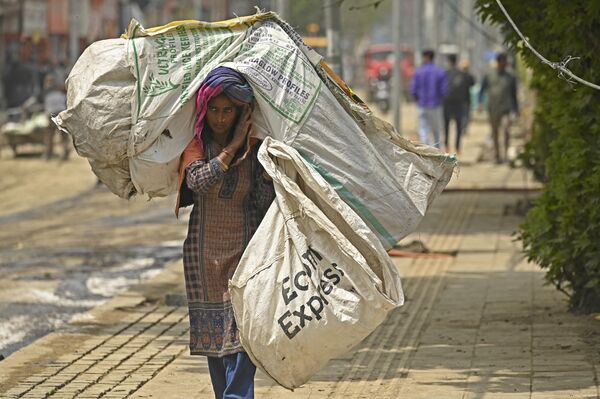Работница несет мешок с мусором по улице в Сринагаре.  - Sputnik Узбекистан