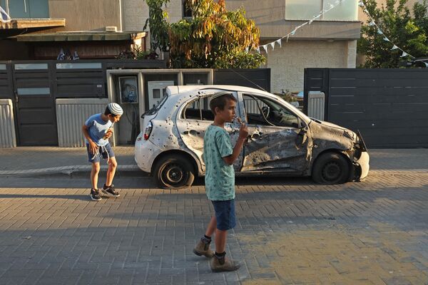 Дети смотрят на поврежденный автомобиль в южном израильском городе Сдерот. - Sputnik Узбекистан