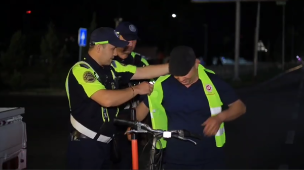 Сотрудники УБДД г. Коканда раздают светоотражающие жилеты, чтобы велосипедисты могли безопасно передвигаться в ночное время. Скриншот видео. - Sputnik Узбекистан