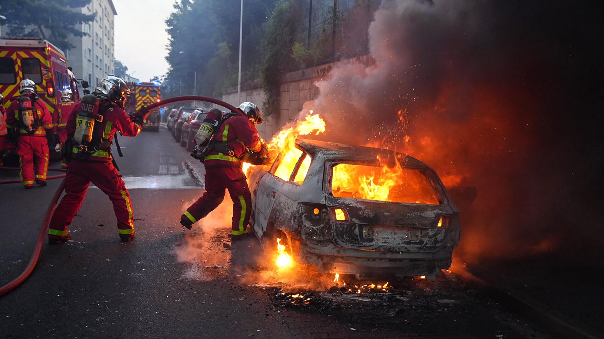Пожарные тушат горящий автомобиль на обочине демонстрации в Нантере, к западу от Парижа, 27 июня 2023 года. - Sputnik Узбекистан, 1920, 28.06.2023