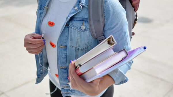 Девушка держит в руке учебники. - Sputnik Узбекистан