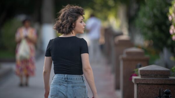 Девушка с короткой прической в шортах идет по тротуару  - Sputnik Узбекистан