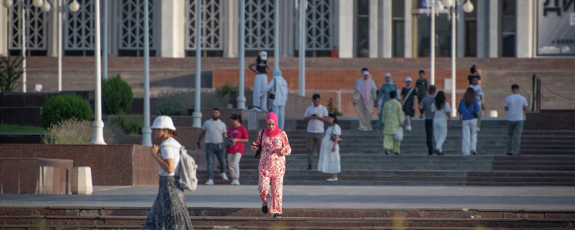 Девушка в платке идет по площади перед дворцом Дружбы народов - Sputnik Узбекистан, 1920, 22.09.2025