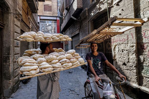 Доставщики передают друг другу подносы с традиционным египетским хлебом в Каире. - Sputnik Узбекистан