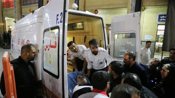 Медики переносят раненого мужчину в машину скорой помощи на месте стрельбы в мавзолее Шах-Черах в иранском Ширазе - Sputnik Узбекистан