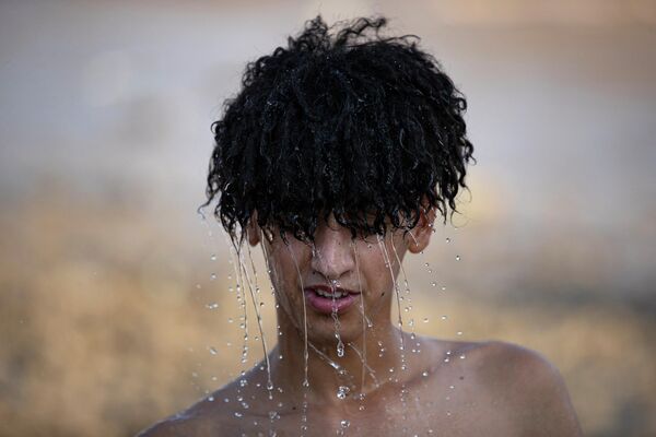 Верующий в иракском городе Басре во время религиозного праздника Арбаин обливается водой, чтобы охладиться в жаркую погоду. - Sputnik Узбекистан