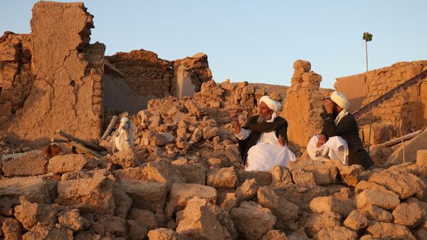 Люди сидят у развалин дома после землетрясения в деревне Сарбуланд Зенде Джана, район провинции Герат, Афганистан - Sputnik Узбекистан
