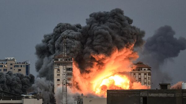 Люди, стоящие на крыше, наблюдают, как шар огня и дыма поднимается над зданием в городе Газа 7 октября 2023 года во время авиаудара Израиля по зданию Палестинской башни.  - Sputnik Узбекистан
