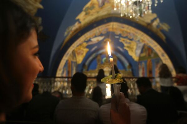 Девушка держит свечу, зажженную от &quot;Благодатного огня&quot; в церкви Святого Порфирия в Газе. - Sputnik Узбекистан