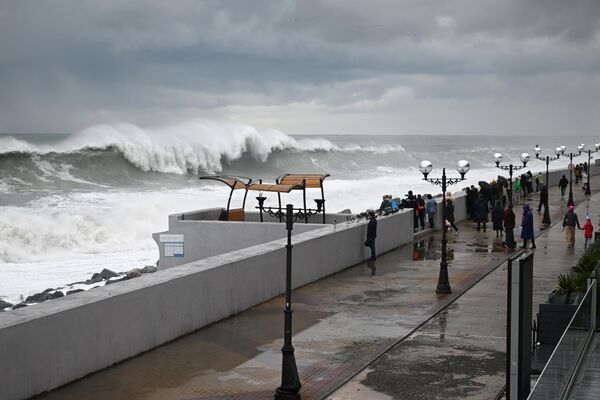 Люди наблюдают за штормом на набережной в Сочи. Волны в море достигали четырех метров. Из-за сильного шторма запретили проход на сочинские пляжи - Sputnik Узбекистан