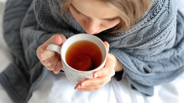 Больная девушка с чашкой горячего чая в постели  - Sputnik Узбекистан