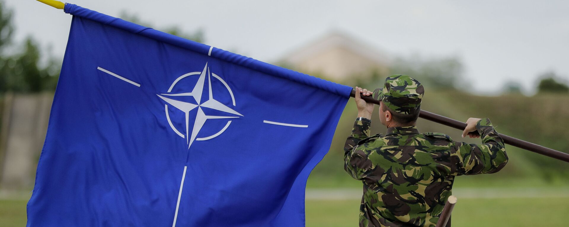 Военнослужащий с флагом НАТО - Sputnik Ўзбекистон, 1920, 21.10.2025