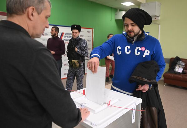 Мужчина голосует на выборах президента России на избирательном участке в школе № 2123 в Москве - Sputnik Узбекистан