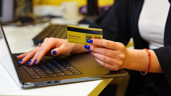 Девушка с кредитной картой в руке перед ноутбуком - Sputnik Ўзбекистон