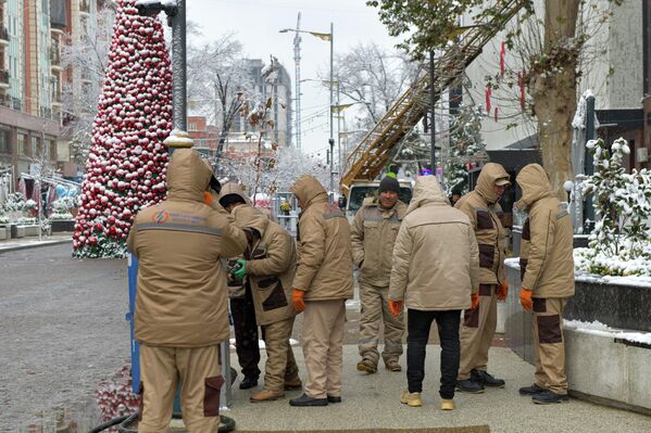 Группа коммунальных рабочих на заснеженной городской улице Группа коммунальных рабочих на заснеженной городской улице - Sputnik Узбекистан