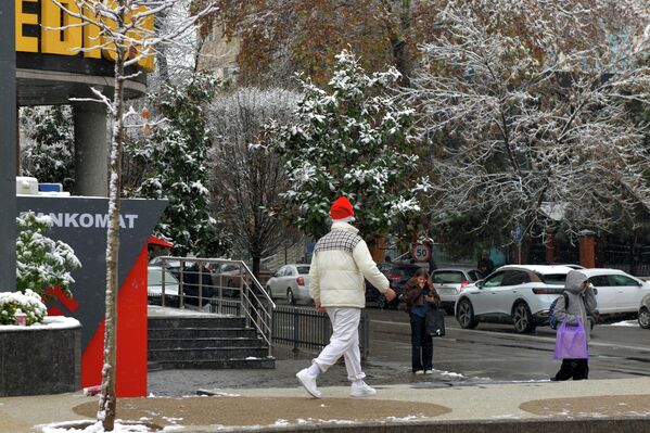 Прохожий в новогодней шапке на заснеженной улице Прохожий в новогодней шапке на заснеженной улице - Sputnik Узбекистан