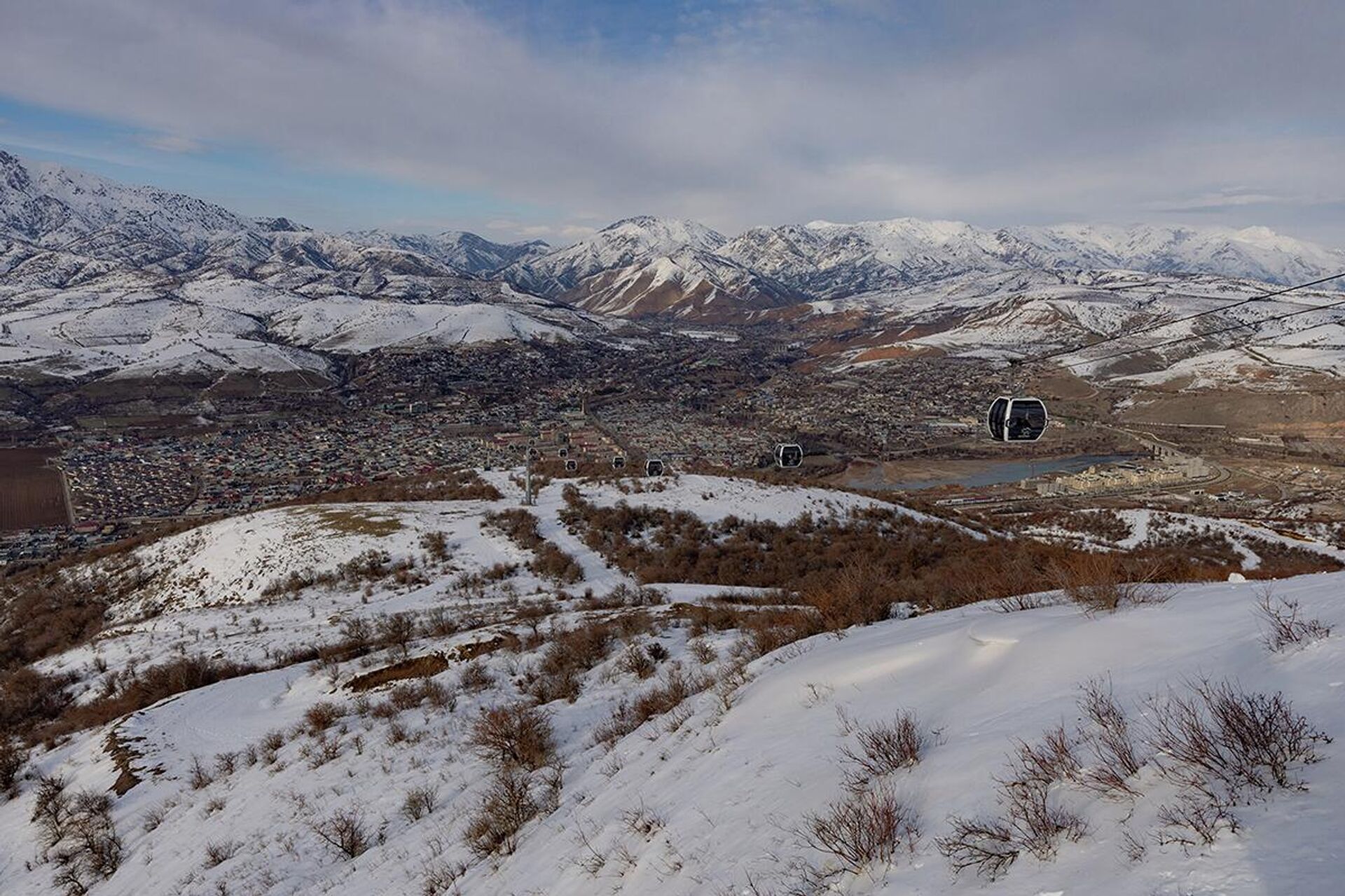 Панорамный вид на горный курорт Чиноркент (Chinorkent. Канатная дорога: На переднем плане видны современные закрытые кабинки (гондолы), которые поднимают туристов на высоту около 1680 метров. - Sputnik Узбекистан, 1920, 11.02.2026