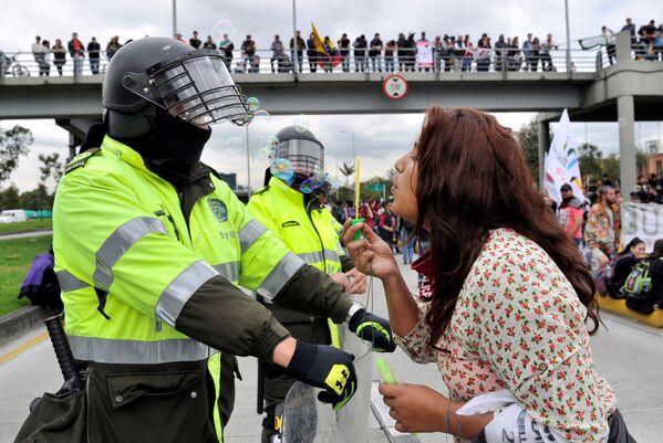 Студентка возле сотрудников полиции во время акции протеста в Боготе, Колумбия - Sputnik Узбекистан