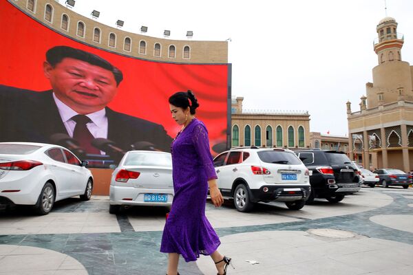 Женщина у гигантского экрана на главной городской площади в Кашгаре, Синьцзян-Уйгурский автономный район, Китай - Sputnik Узбекистан