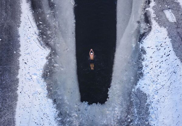 Человек плавает в частично замерзшем озере в Шэньяне, провинция Ляонин - Sputnik Узбекистан