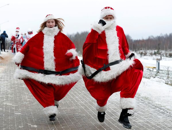 Белорусская пара в костюмах Дедов Морозов принимает участие в новогоднем забеге вокруг озера в Минске, Беларусь - Sputnik Узбекистан