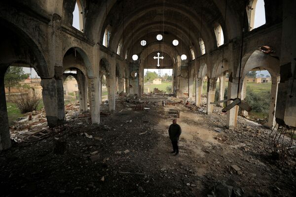 Мужчина среди развалин церкви Девы Марии в деревне Тель-Насри, Сирия  - Sputnik Узбекистан